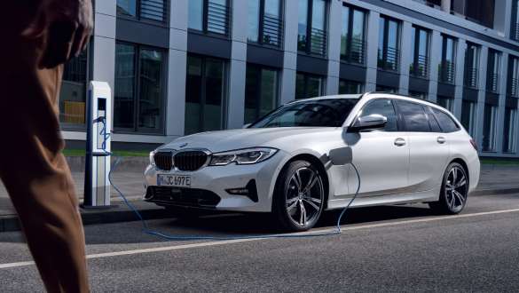 Plug-in-Hybrid BMW 3er Touring 2021 (G21) Dreiviertel-Frontansicht ladend Plug-in-Hybrid BMW 3er Touring 2021 (G21) Dreiviertel-Frontansicht ladend vor Gebäude