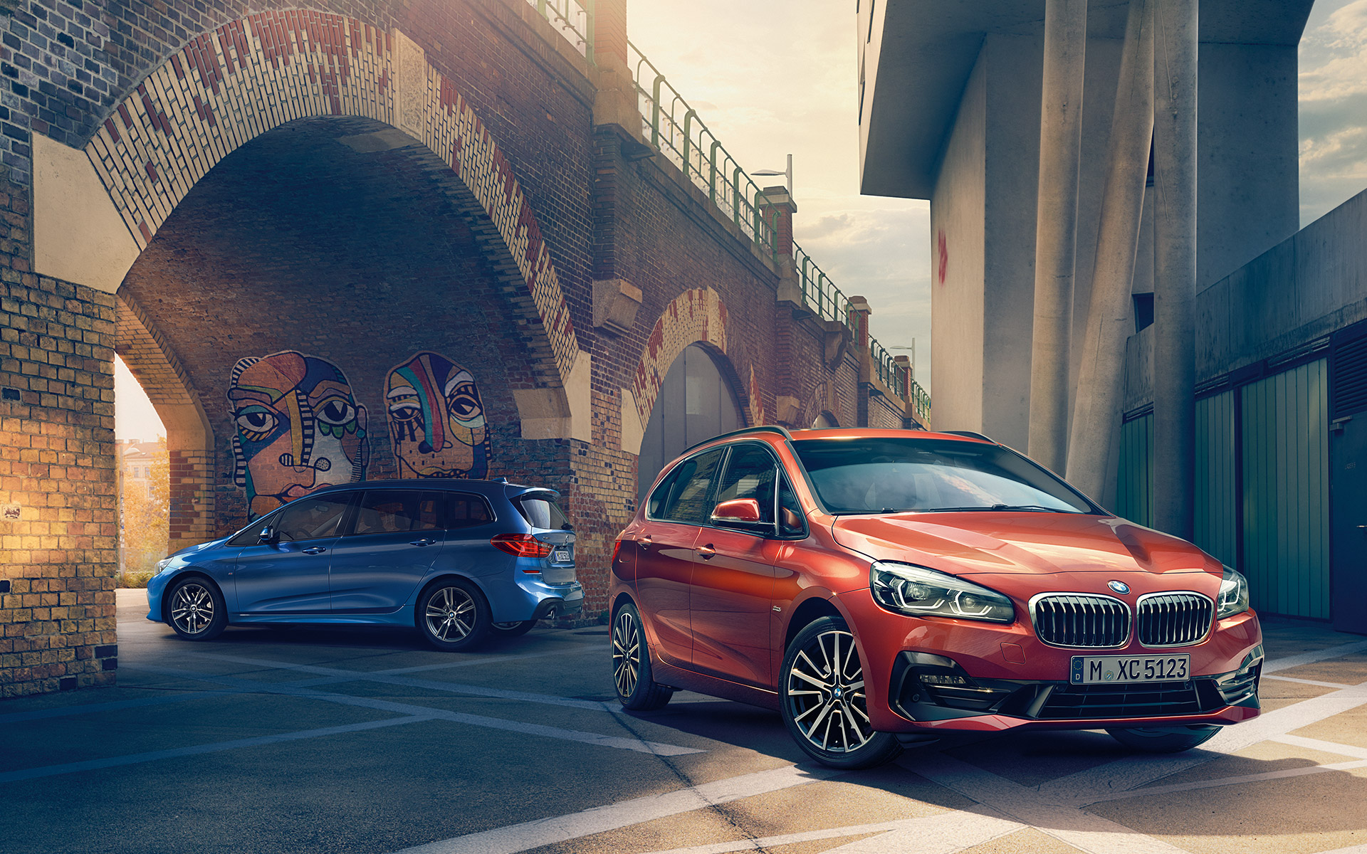Blauer und orangener BMW 2er Active Tourer auf einem Parkplatz Blauer und orangener BMW 2er Active Tourer auf einem Parkplatz