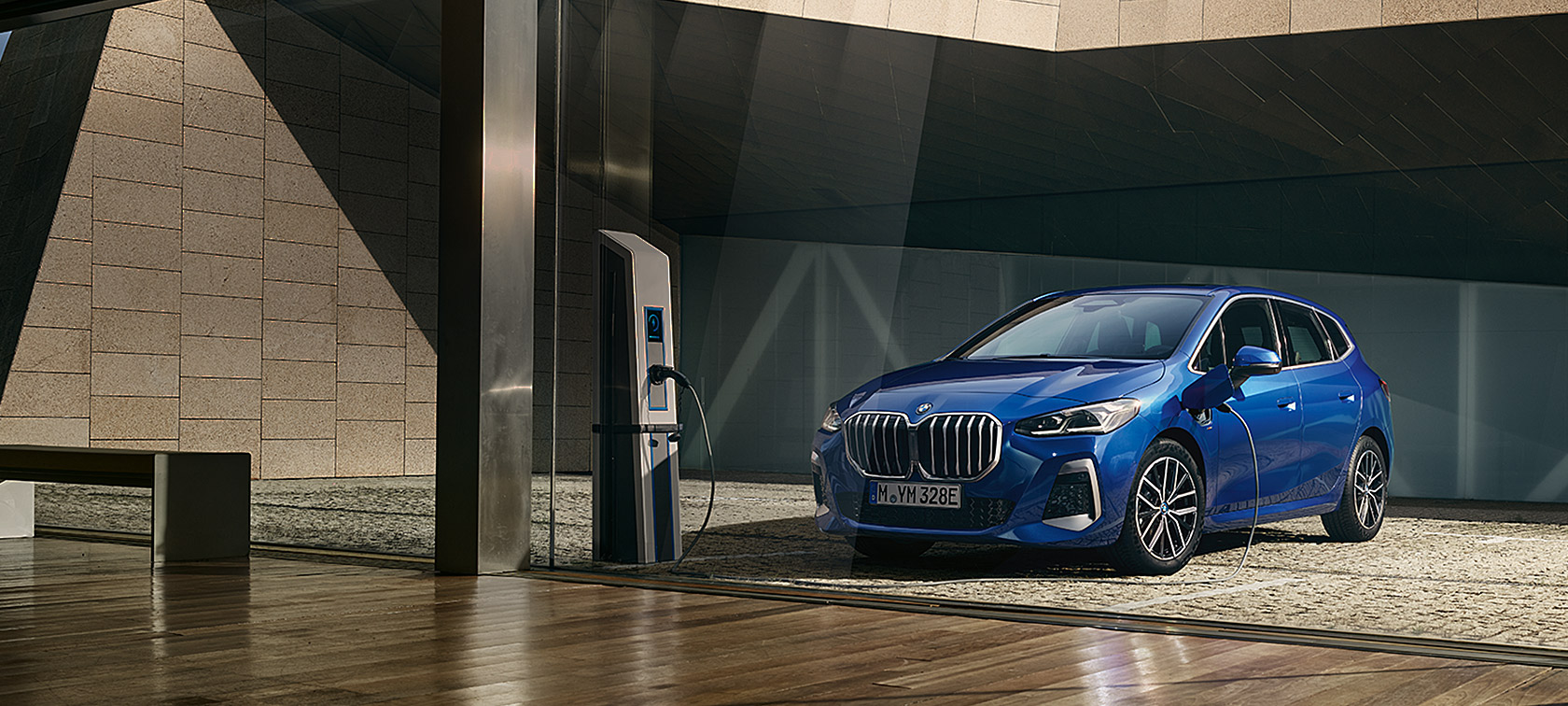 BMW 2er Active Tourer 230e xDrive Plug-in-Hybrid U06 2021 M Portimao Blau metallic Dreiviertel-Frontansicht an der Ladesäule