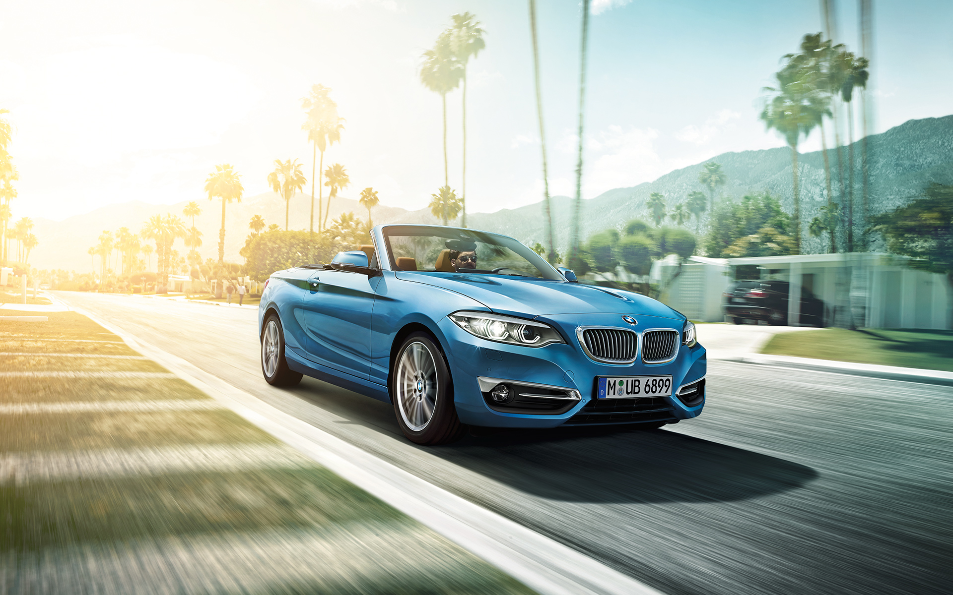 BMW 2er Cabrio fährt entlang einer Straße mit Palmen BMW 2er Cabrio fährt entlang einer Straße mit Palmen