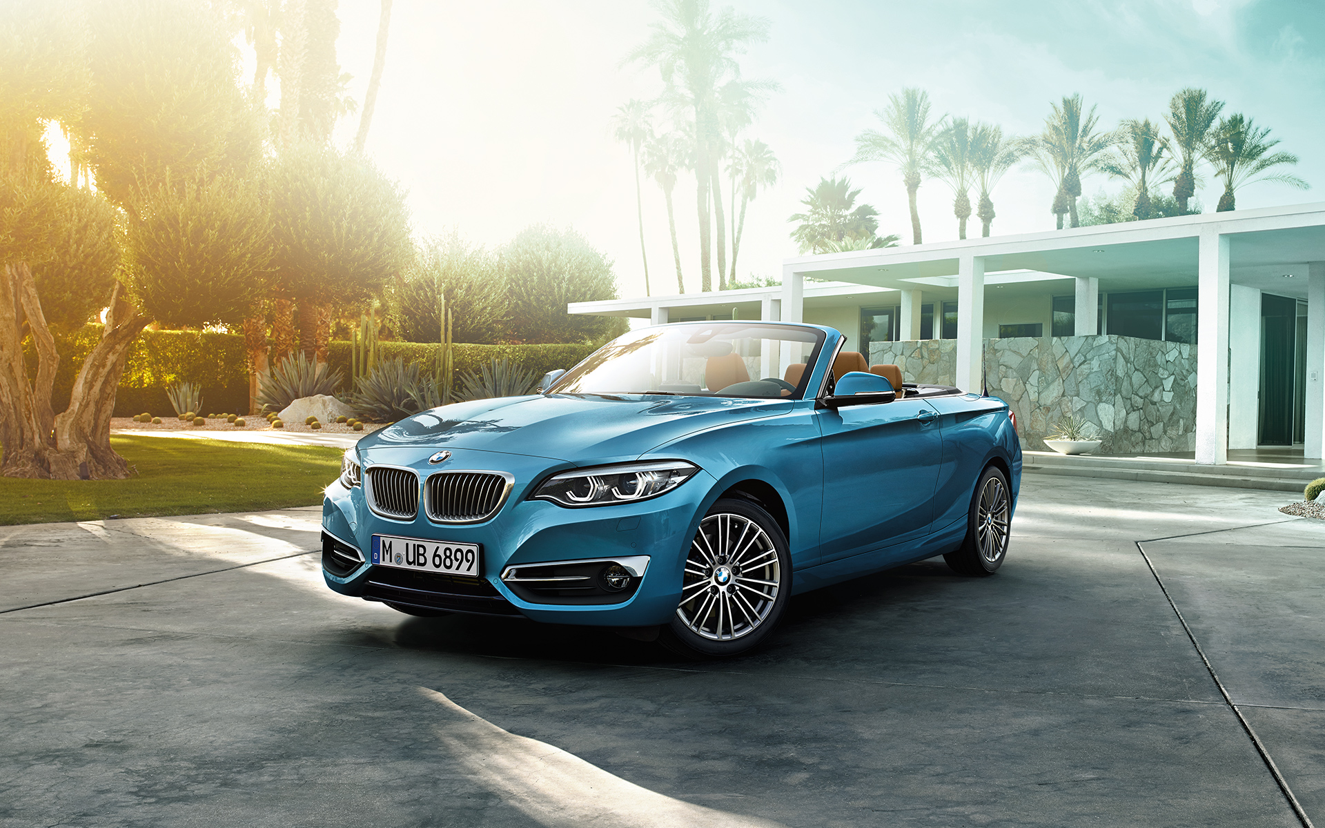 BMW 2er Cabrio mit geöffnetem Verdeck geparkt vor einem modernen Haus BMW 2er Cabrio mit geöffnetem Verdeck geparkt vor einem modernen Haus