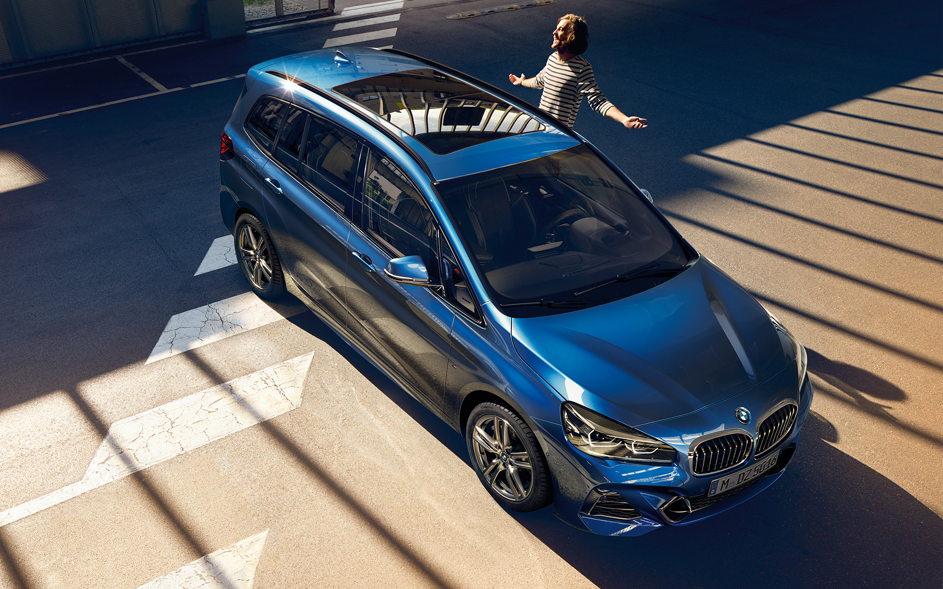 Junger Mann steht vor einem BMW 2er Gran Tourer Junger Mann steht vor einem BMW 2er Gran Tourer