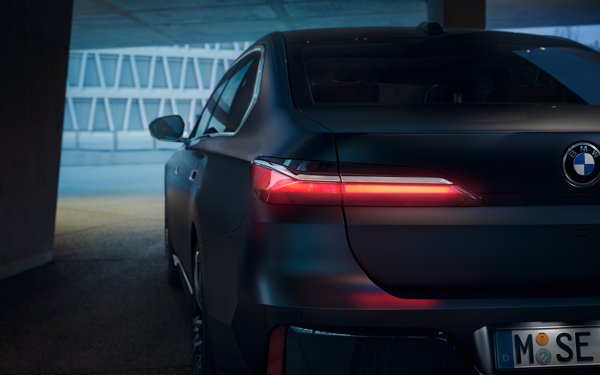 BMW 7er Limousine G70 ICE 740d xDrive M Sportpaket BMW Individual Frozen Deep Grey metallic Heckansicht mit rot leuchtendem Rücklicht im Tunnel