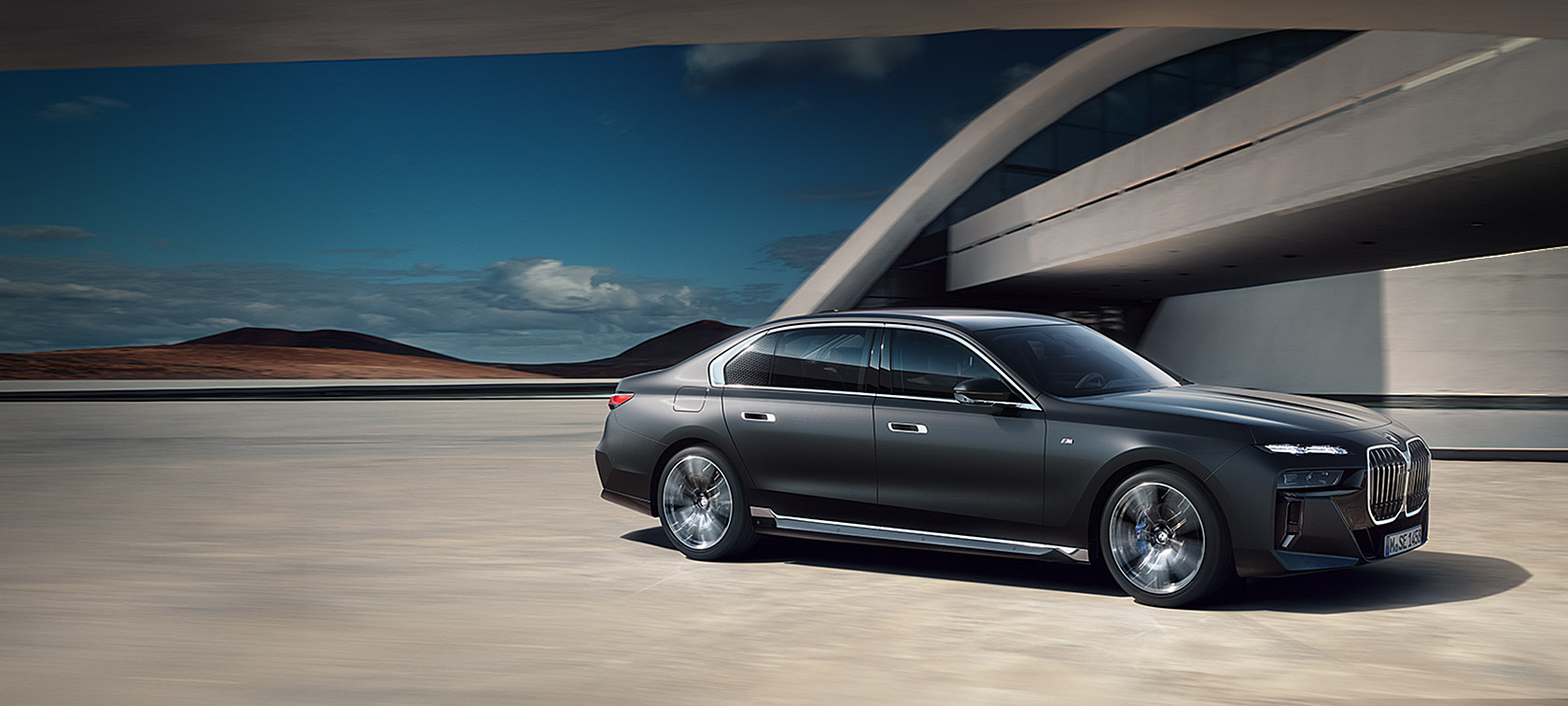 BMW 7er Limousine G70 ICE M Sportpaket BMW Individual Frozen Deep Grey metallic 3/4 Frontansicht stehend vor Gebäude