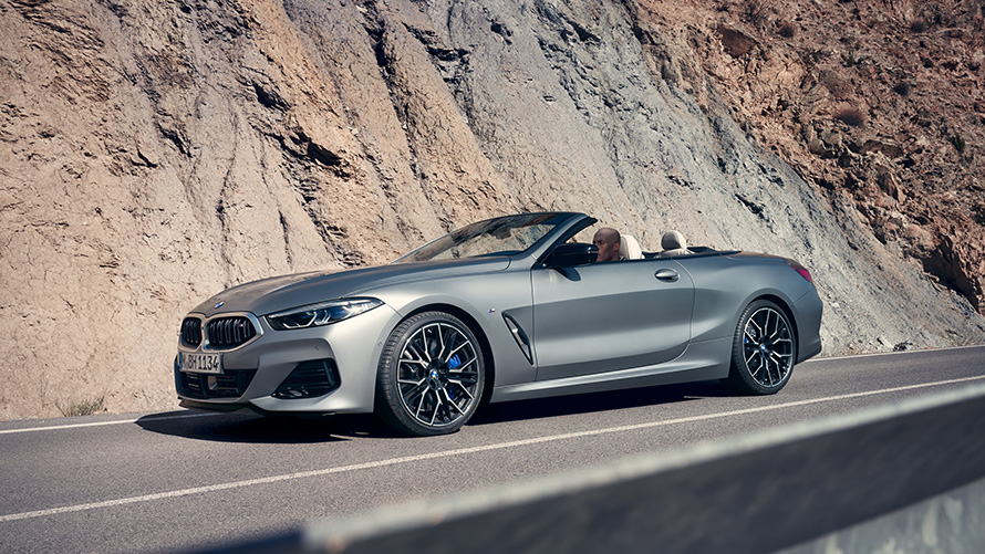 BMW 8er Cabriolet G14 LCI Facelift 2022 mit geöffnetem Verdeck fahrend entlang Bergwand BMW 8er Cabrio G14 LCI Facelift 2022 BMW Individual Frozen Pure Grey metallic Seitenansicht mit geöffnetem Verdeck fahrend entlang Bergwand
