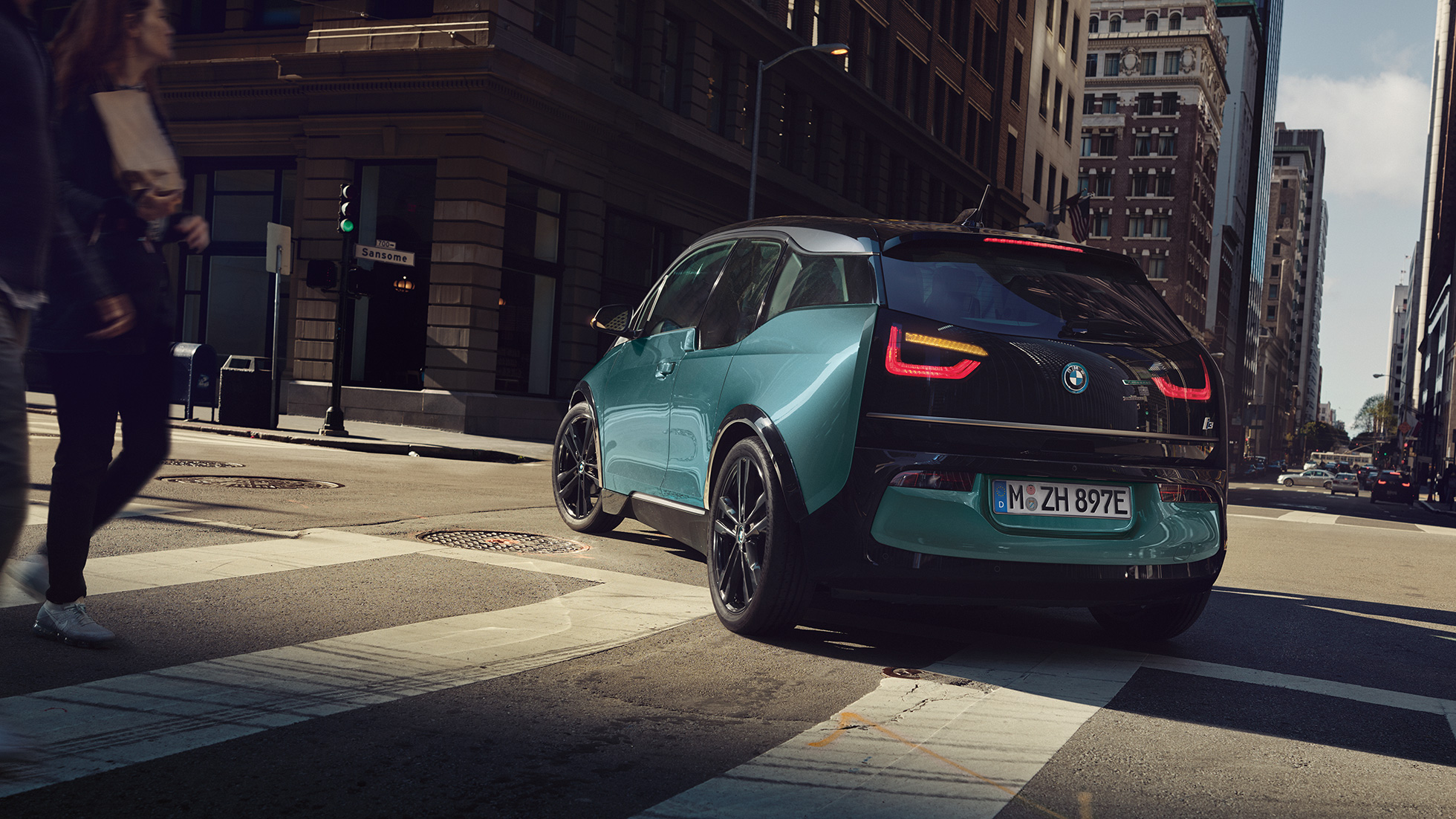 BMW i3 2018 Dreiviertel-Heckansicht fahrend BMW i3 I01 2018 Jucarobeige mit Akzent Frozen Grey metallic Dreiviertel-Heckansicht fahrend in urbaner Kulisse