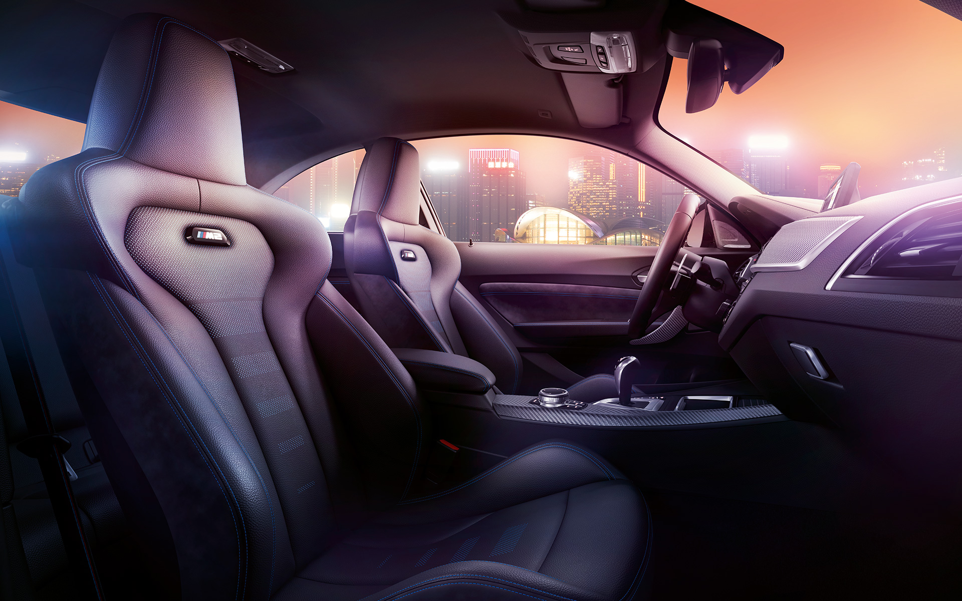 BMW M2 Competition Sportsitze Cockpit und M Sportsitze des BMW M2 Competition, nächtliche Skyline im Hintergrund.