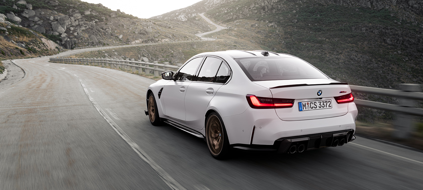 BMW M3 CS G80 Dreiviertel Heckansicht fahrend auf der Straße im Gebirge
