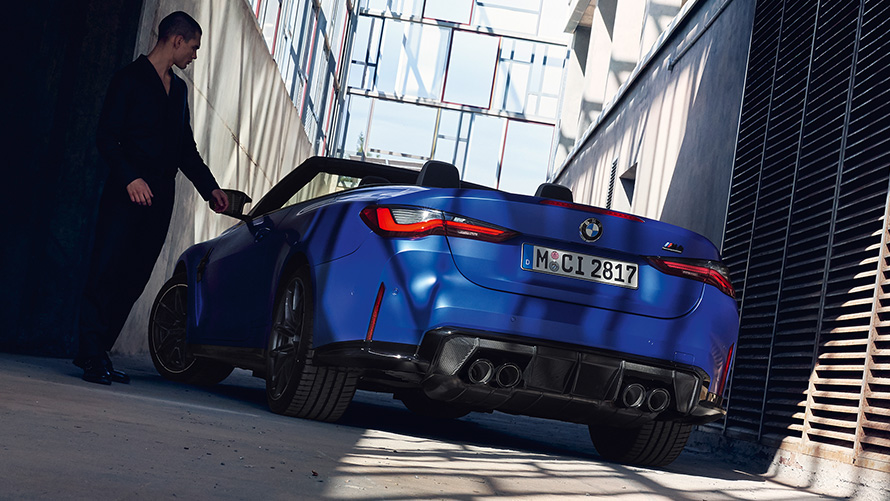 BMW M4 Competition Cabrio mit M xDrive G83 2021 BMW Individual Frozen Portimao Blau metallic Dreiviertel-Heckansicht mit Mann