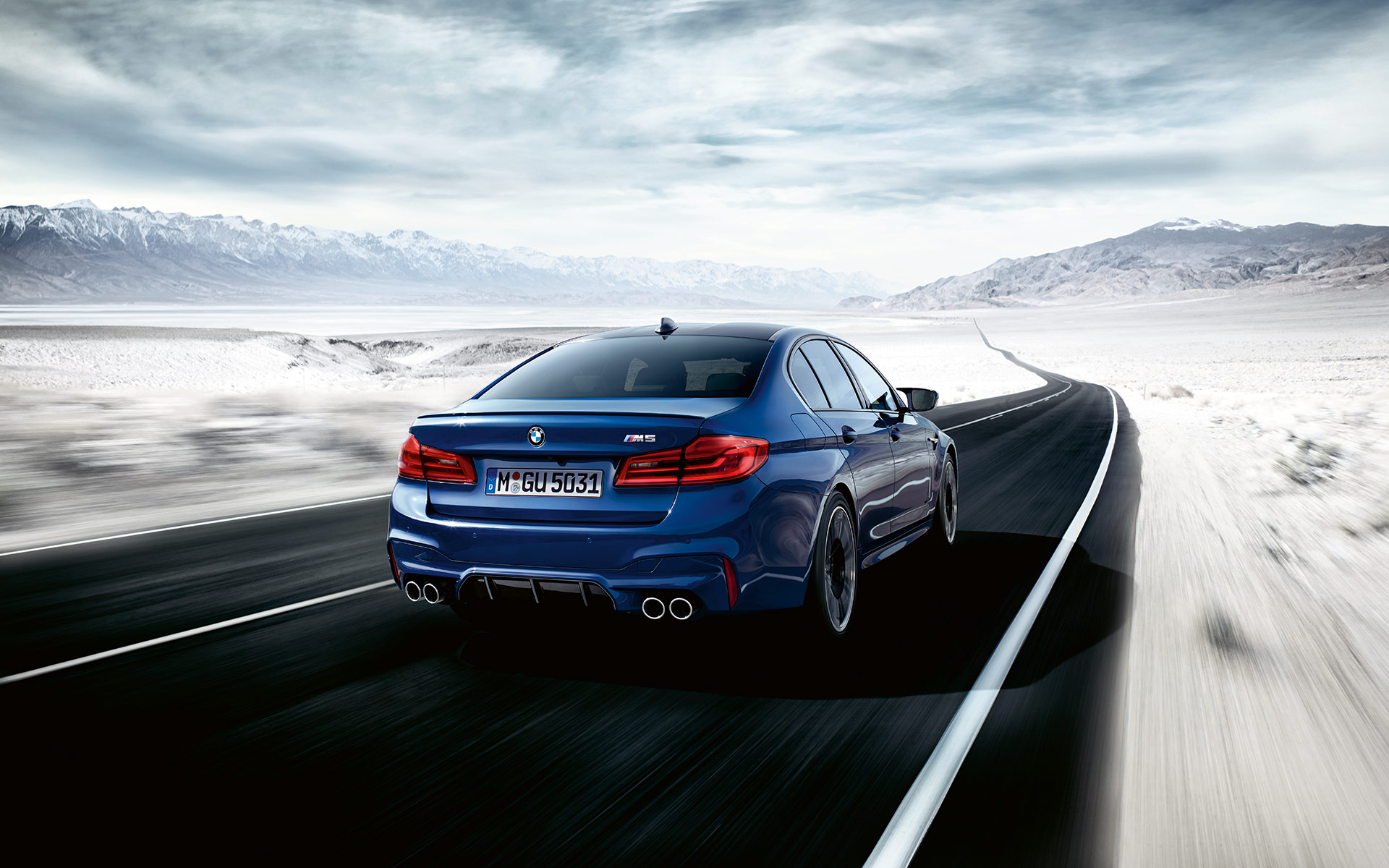 BMW M5 fährt auf der Straße in einer Schneelandschaft, Rückansicht BMW M5 fährt auf der Straße in einer Schneelandschaft, Rückansicht
