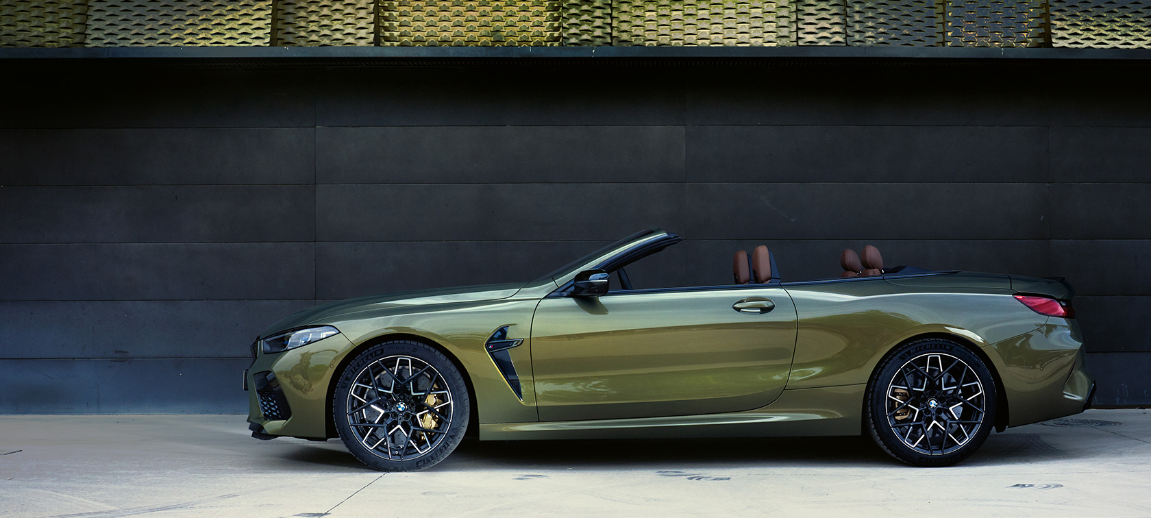 BMW M8 Competition Cabriolet F91 LCI Facelift 2022 Seitenansicht stehend BMW M8 Competition Cabriolet F91 LCI Facelift 2022 BMW Individual Brass metallic Seitenansicht stehend mit geöffneter Tür und weiblichem Model