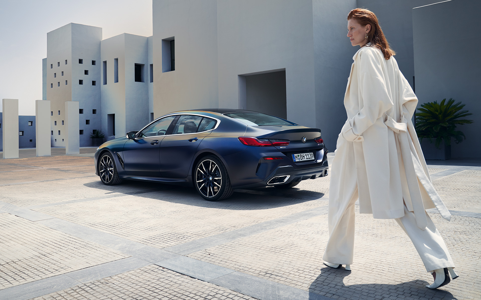 BMW M850i xDrive Gran Coupé G16 LCI Facelift 2022 BMW Individual Frozen Tansanitblau metallic Dreiviertel-Heckansicht mit weiblichem Model