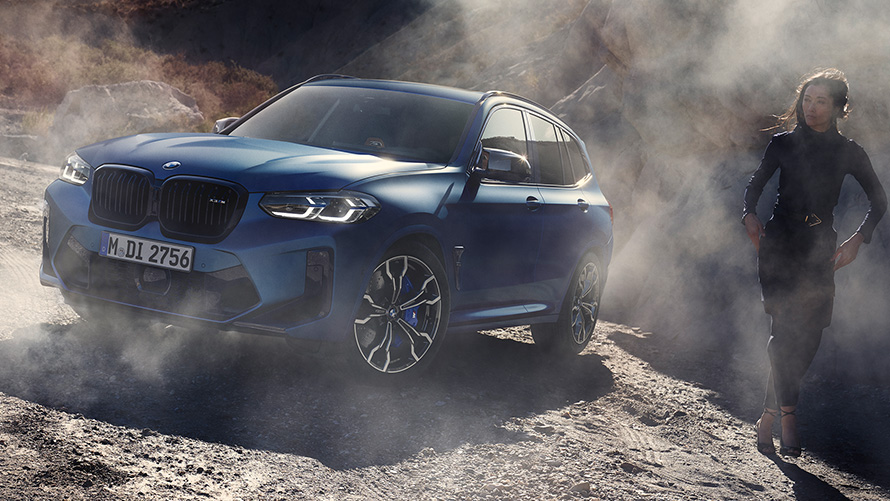 BMW X3 M Competition F97 LCI Facelift 2021 Frozen Marina Bay Blau metallic Dreiviertel-Frontansicht stehend in steinigem Gelände mit Frau