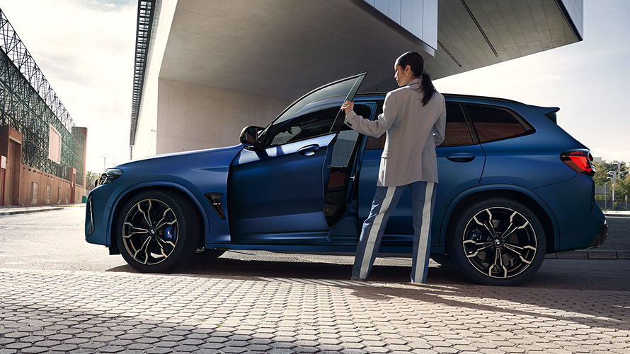 BMW X3 M Competition F97 LCI Facelift 2021 Frozen Marina Bay Blau metallic Seitenansicht mit geöffneter Tür und Frau