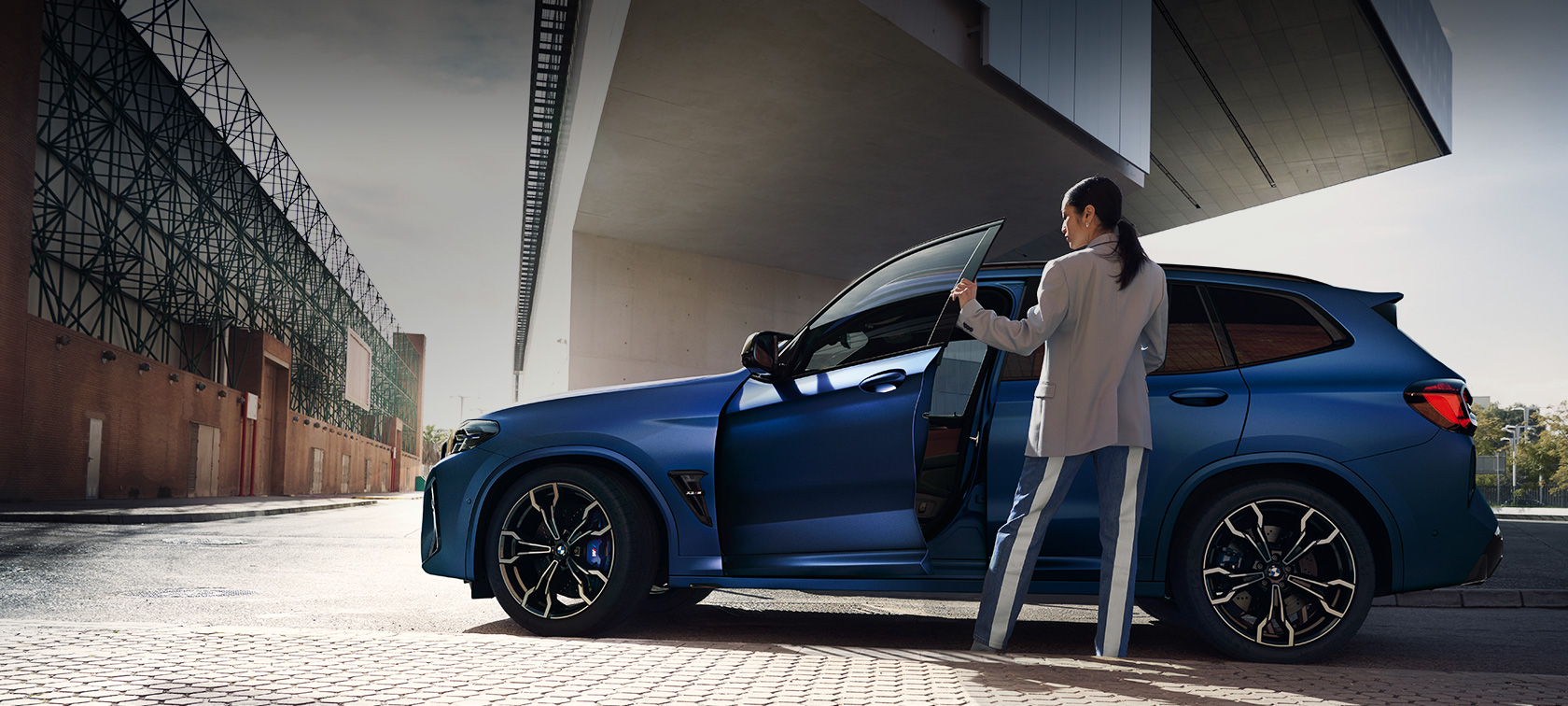 BMW X3 M Competition F97 LCI Facelift 2021 Seitenansicht stehend BMW X3 M Competition F97 LCI Facelift 2021 BMW Individual Frozen Portimao Blau metallic Seitenansicht stehend mit geöffneter Tür und weiblichem Model