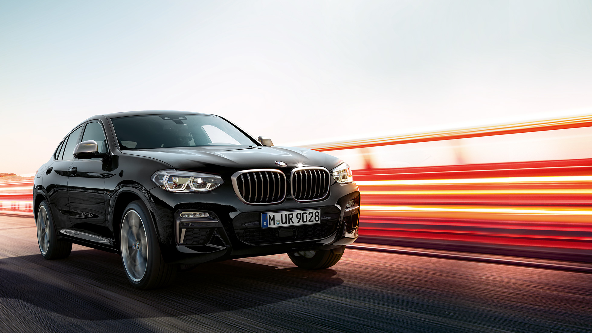 BMW X4 M40i, Dreiviertel-Heckansicht. BMW X4 M40i in Saphirschwarz metallic, fahrend, Exterieur, Dreiviertel-Heckansicht mit Lichtstreifen.