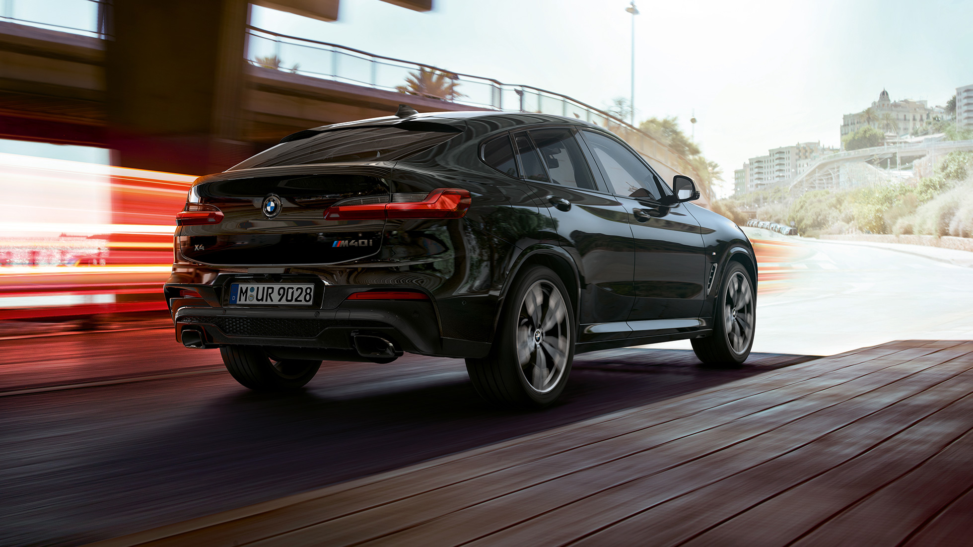 BMW X4 M40i, Dreiviertel-Heckansicht. BMW X4 M40i in Saphirschwarz metallic, Exterieur, Dreiviertel-Heckansicht rechts mit Lichtstreifen.