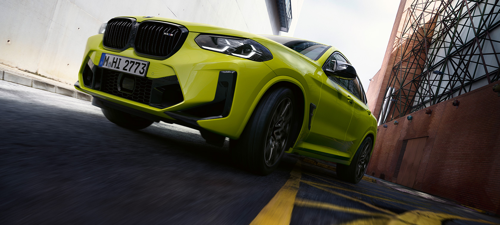 BMW X4 M Competition F98 LCI Facelift 2021 Sao Paulo Gelb Dreiviertel-Frontansicht mit Untersicht fahrend durch Häuserschlucht