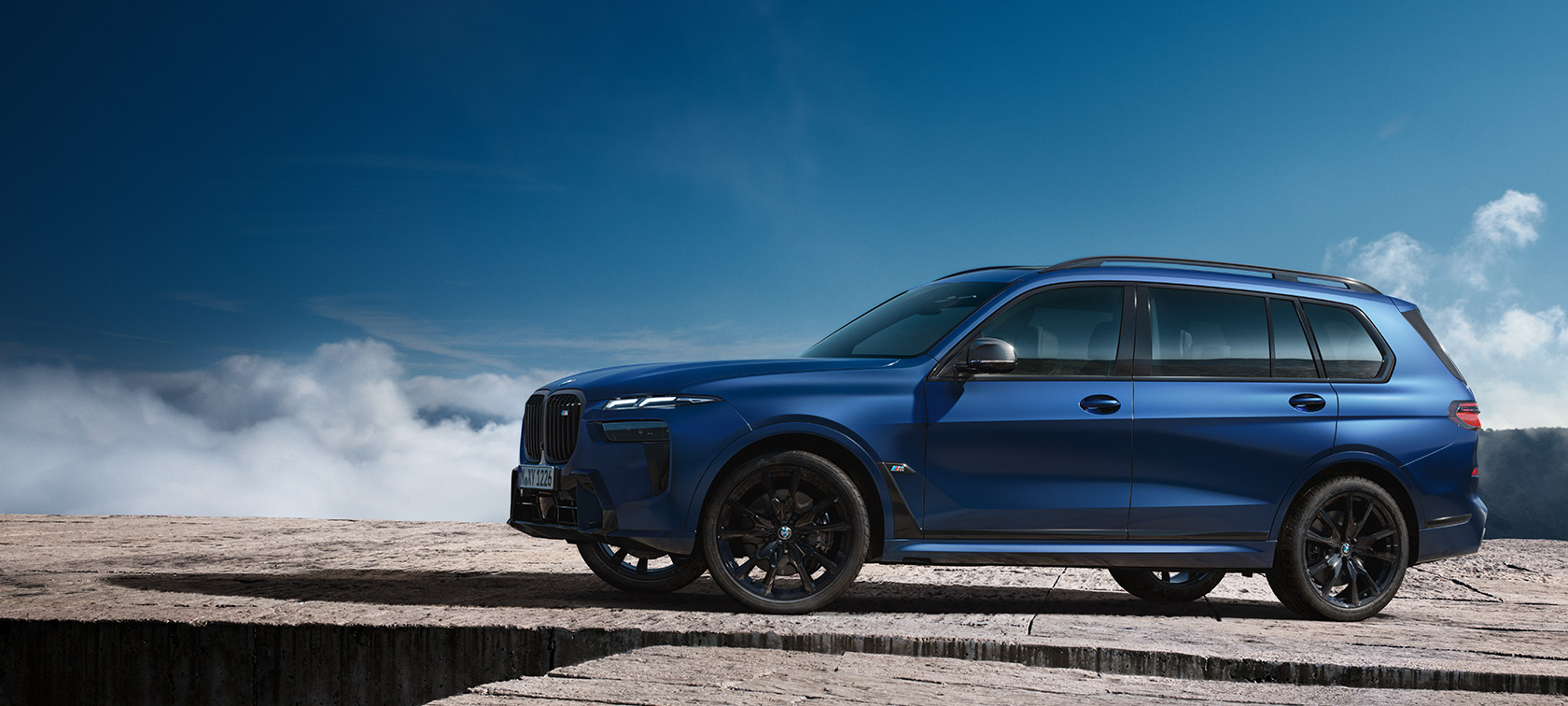 BMW X7 M60i xDrive G07 LCI Frozen Marina Bay Blue Seitenansicht stehend vor Berglandschaft