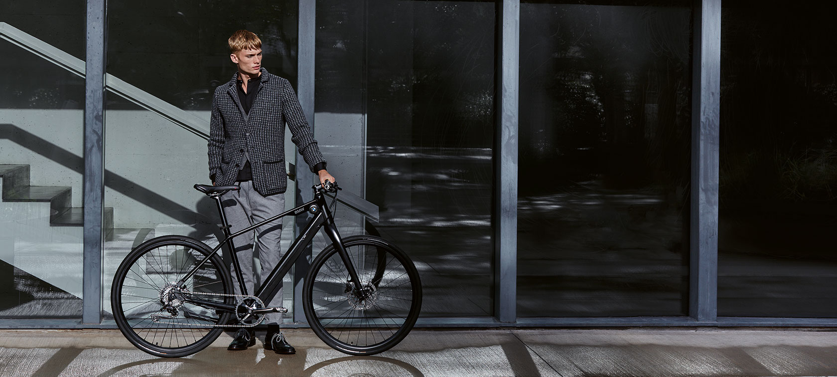 Design und Funktion. Ein Mann steht in lässiger Körperhaltung neben einem BMW Urban Hybrid E-Bike.