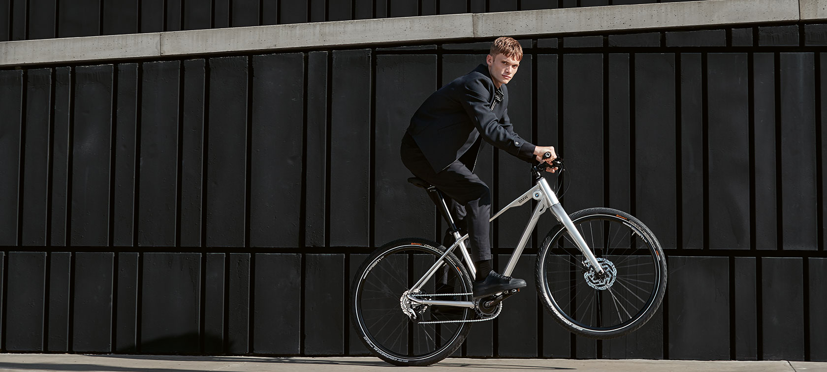 BMW Bikes. Zu sehen ist ein junger Mann, der auf einem BMW Cruise Bike einen dynamischen Wheelie macht.