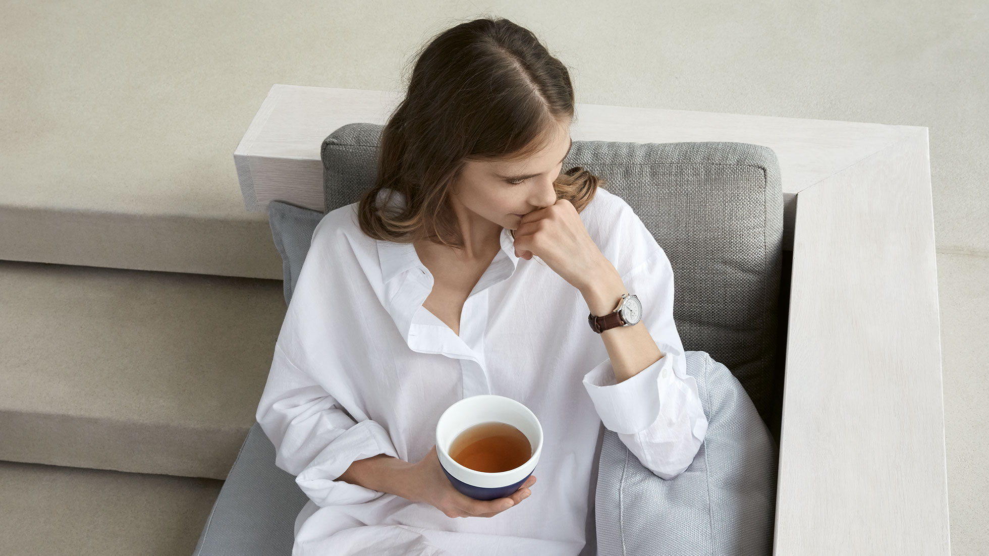 Zeit zum Genießen. Zeit für die BMW Armbanduhr Day Date für Damen. Verträumt im weißen Hemd zeigt ein weibliches Model die BMW Armbanduhr Day Date für Damen.