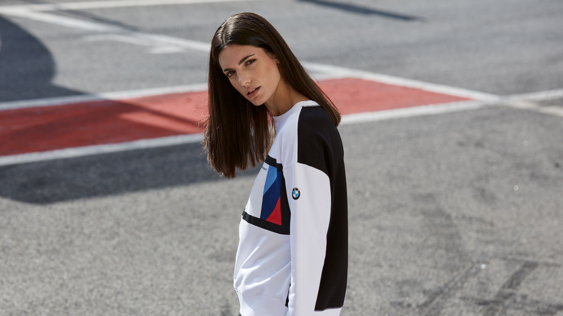 Der BMW M Motorsport Sweater für Damen sorgt für einen starken Auftritt. Auf dem Bild trägt eine junge Frau den BMW M Motorsport Sweater für Damen.