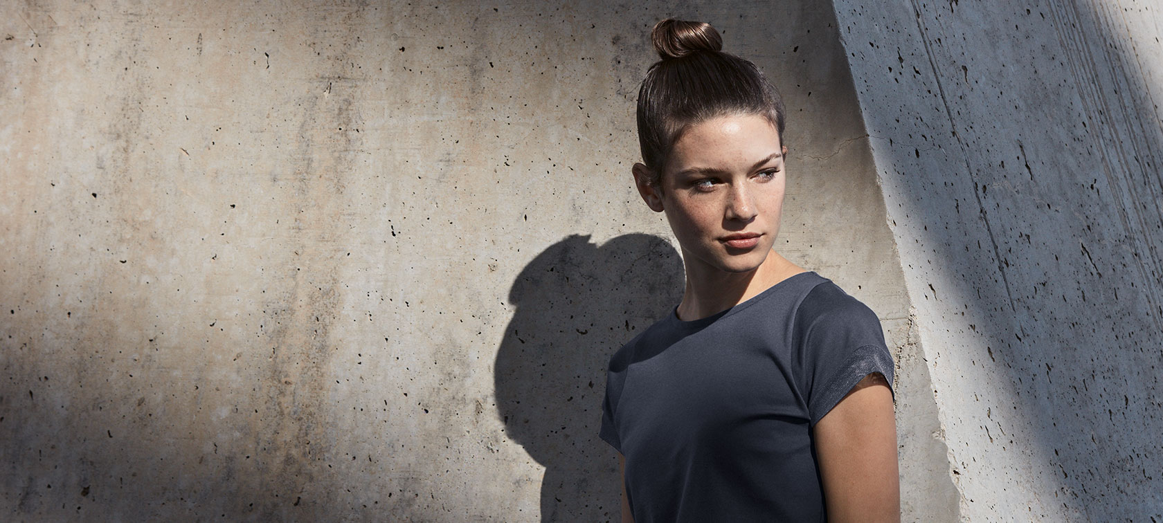Im Bild sehen Sie eine junge Frau, die ein T-Shirt aus einer Kollektion von BMW Lifestyle für Damen trägt. Im Bild sehen Sie eine junge Frau, die ein T-Shirt aus einer Kollektion von BMW Lifestyle für Damen trägt.