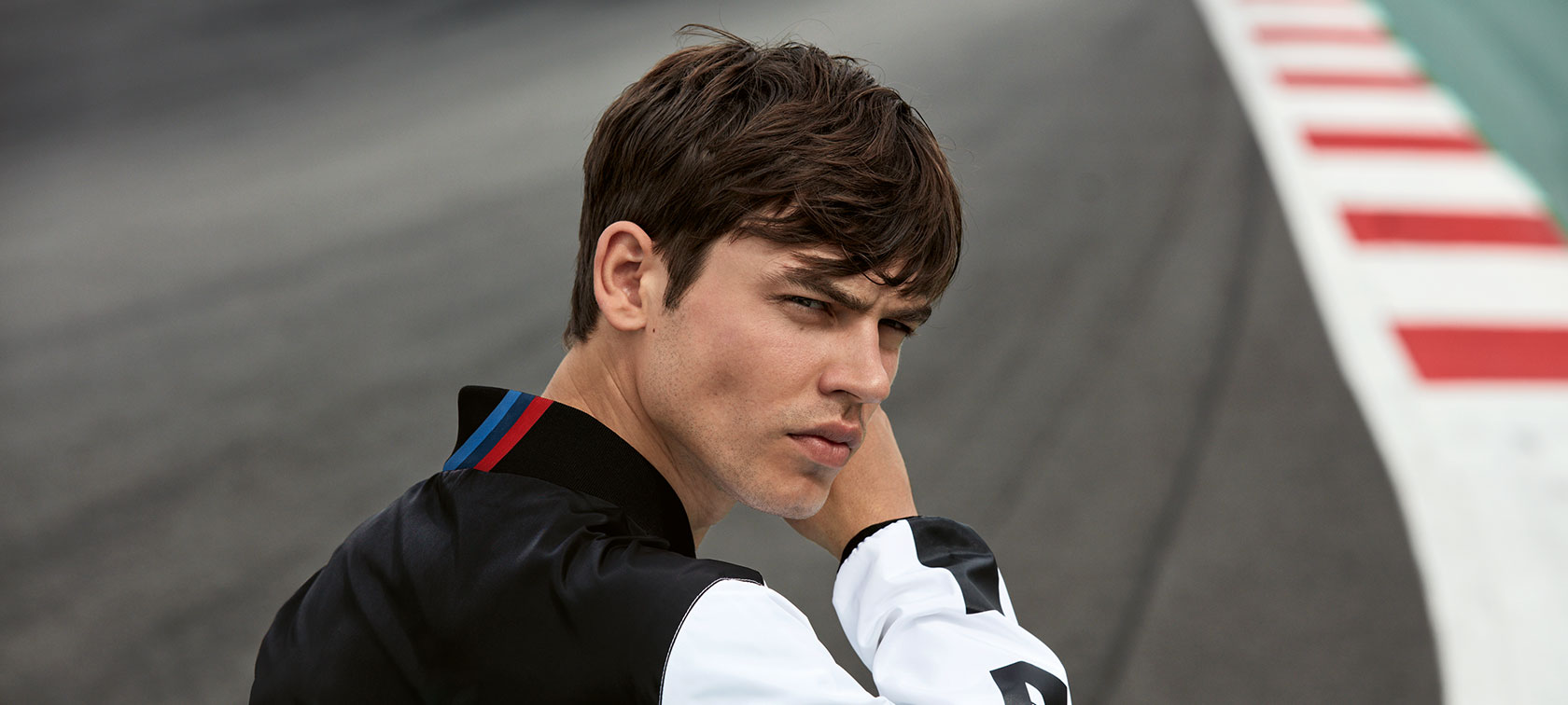 Ein junger Mann präsentiert die BMW M Motorsport Jacke für Herren. Ein junger Mann präsentiert die BMW M Motorsport Jacke für Herren.