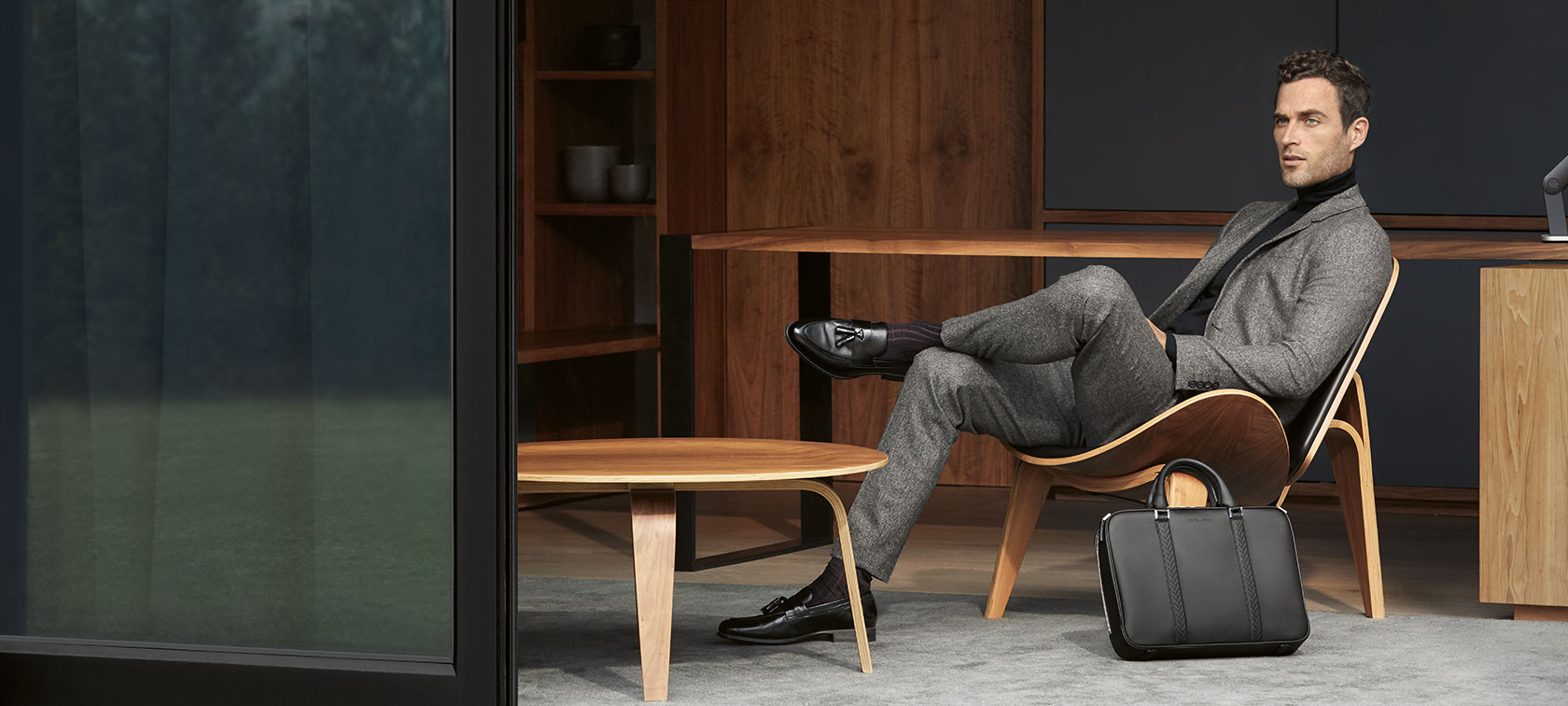 Ein Mann sitzt auf einem Holzstuhl und präsentiert Produkte der The Collection. Ein Mann sitzt auf einem Holzstuhl und präsentiert Produkte der The Collection.