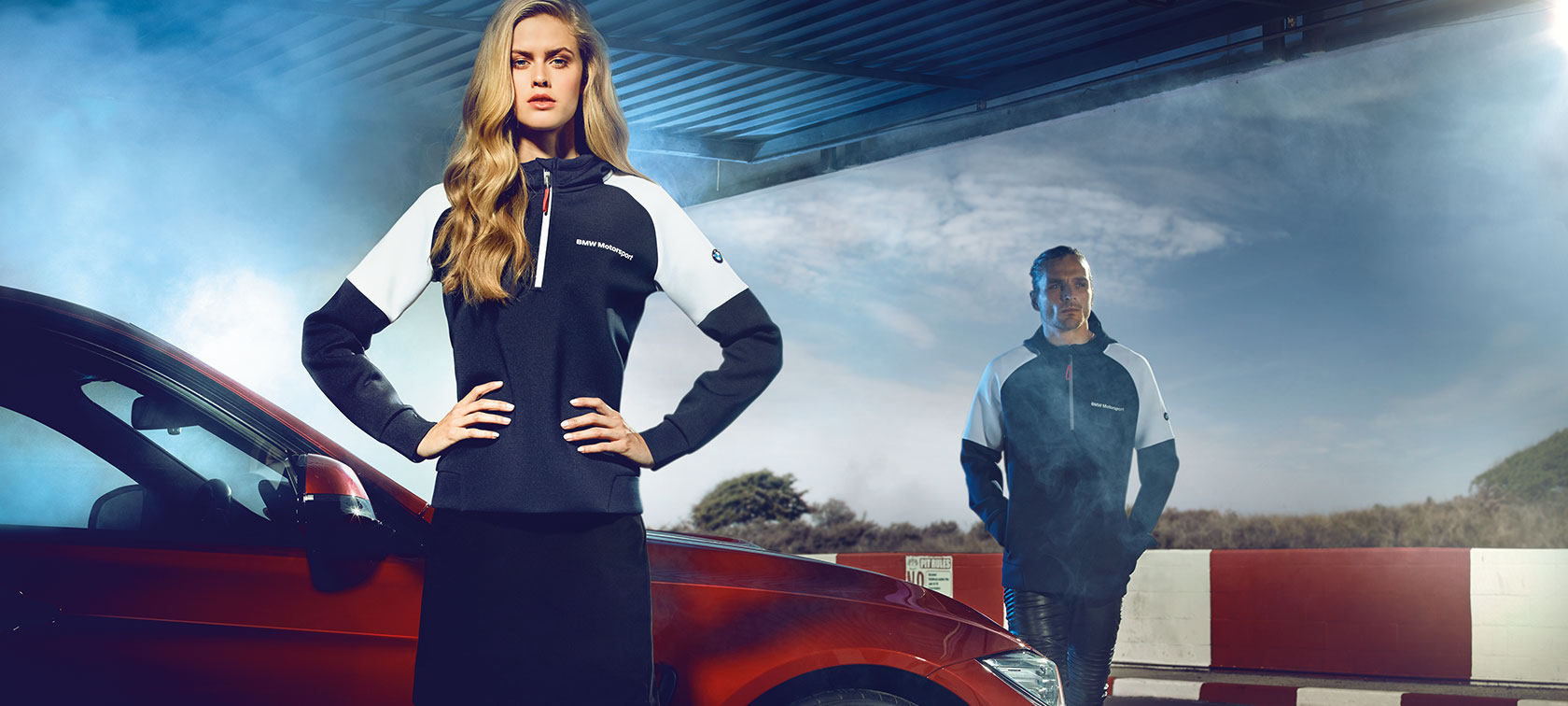 Mann und Frau in Bekleidung der BMW Motorsport Collection. Mann und Frau in Bekleidung der BMW Motorsport Collection.