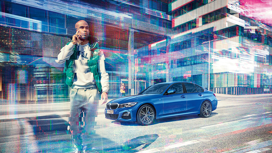 Blauer BMW mit telefonierendem Mann Mann telefoniert mit Handy, im Hintergrund ein blauer BMW vor Stadtkulisse