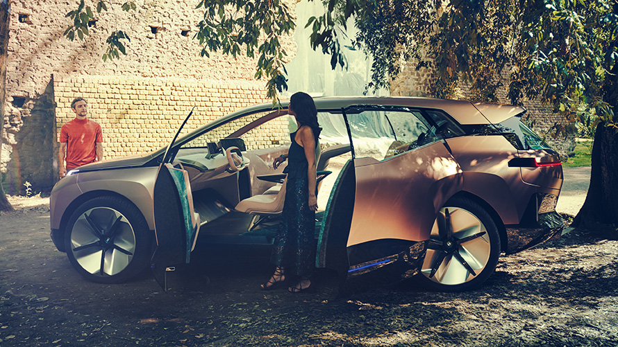 Seite BMW Vision iNEXT Seite BMW Vision iNEXT mit Frau an geöffneter Tür und Mann im Hintergrund