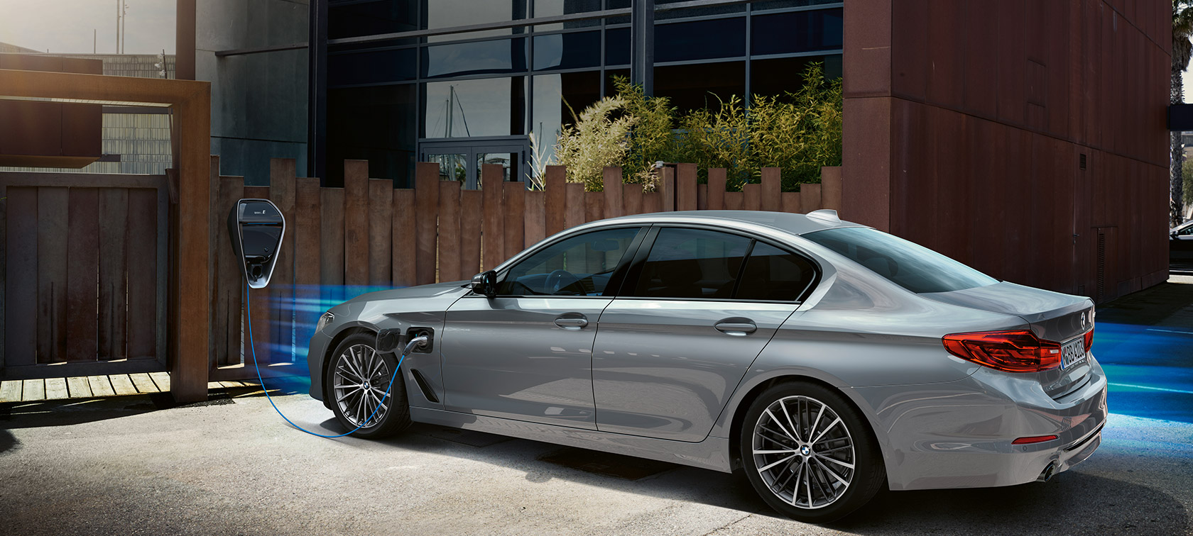 BMW 530e in Dreiviertel-Heck an der Ladestation.