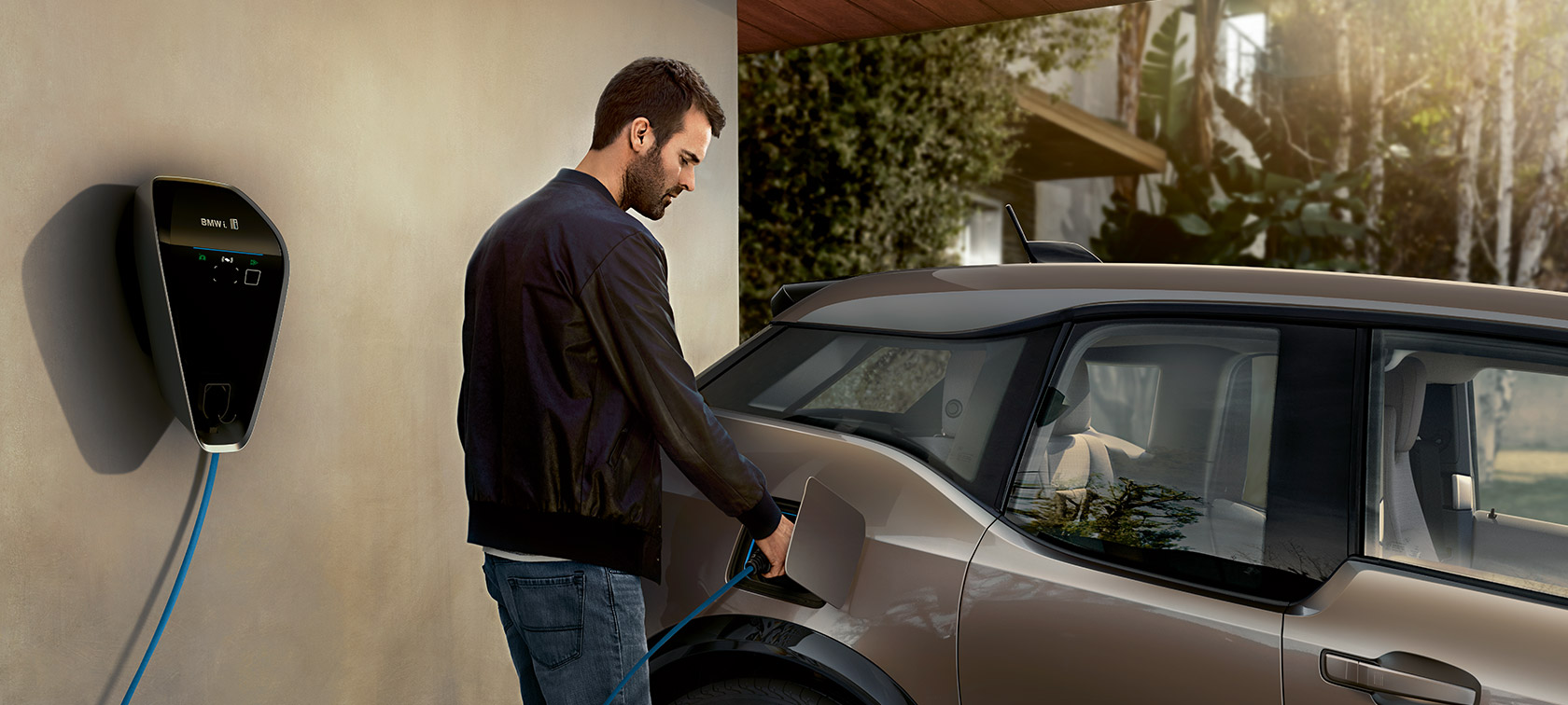 Mann lädt BMW i3 an der BMW i Wallbox auf.