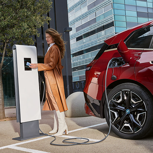 BMW iX i20 an Ladesäule Frau mit BMW Charging Card