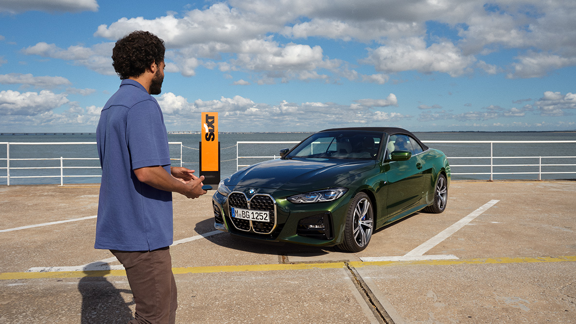 BMW Add-On Mobility App Video BMW Add-On Mobility App Video Mann mit Smartphone in der Hand vor BMW 4er Cabrio und SIXT Schriftzug im Hintergrund