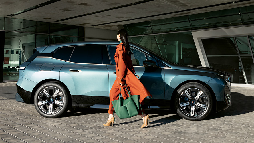 BMW Digital Key nutzen BMW Digital Key Nutzen BMW iX i20 Seitenansicht mit Frau im Vordergrund