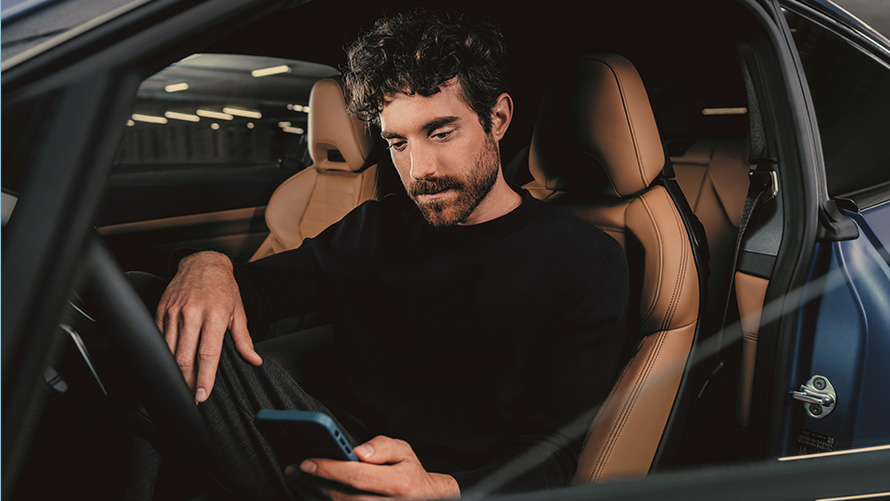Mann sitzt im BMW Mann sitzt im BMW und guckt auf sein Smartphone