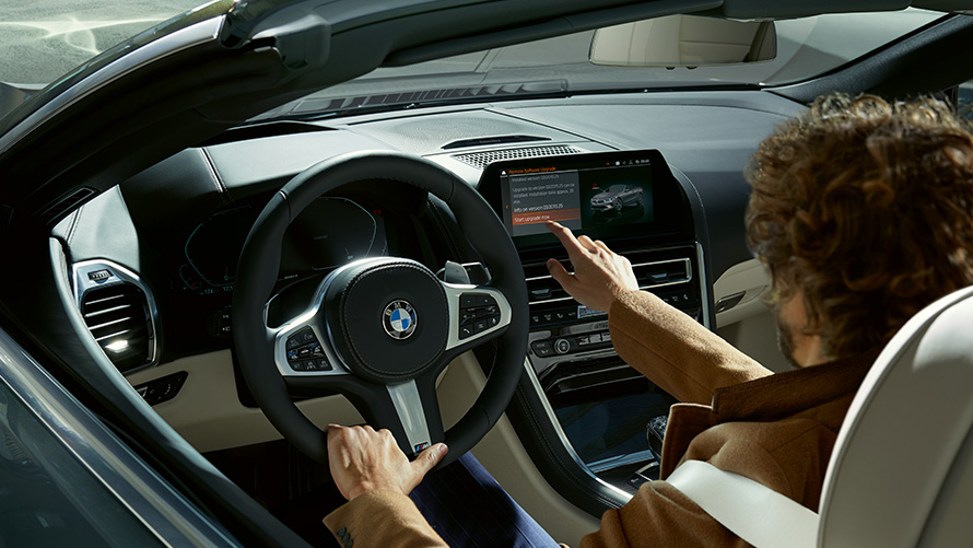 Remote Software Upgrade Remote Software Upgrade Mann sitzt in BMW und bedient das Control Display