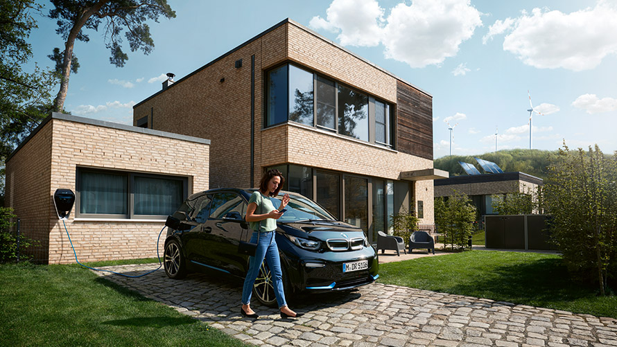 Digital Charging Service Frau nutzt zu Hause Funktion „Digital Charging Service“ über Smartphone für ihren BMW i3