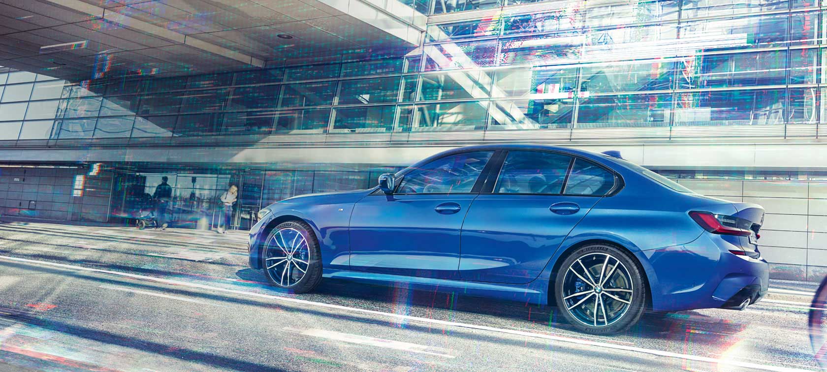 BMW 3er Limousine (G20), Seitenansicht Seitenansicht der fahrenden BMW 3er Limousine (G20) in Portimao Blau bei Tag unter Glasgebäude