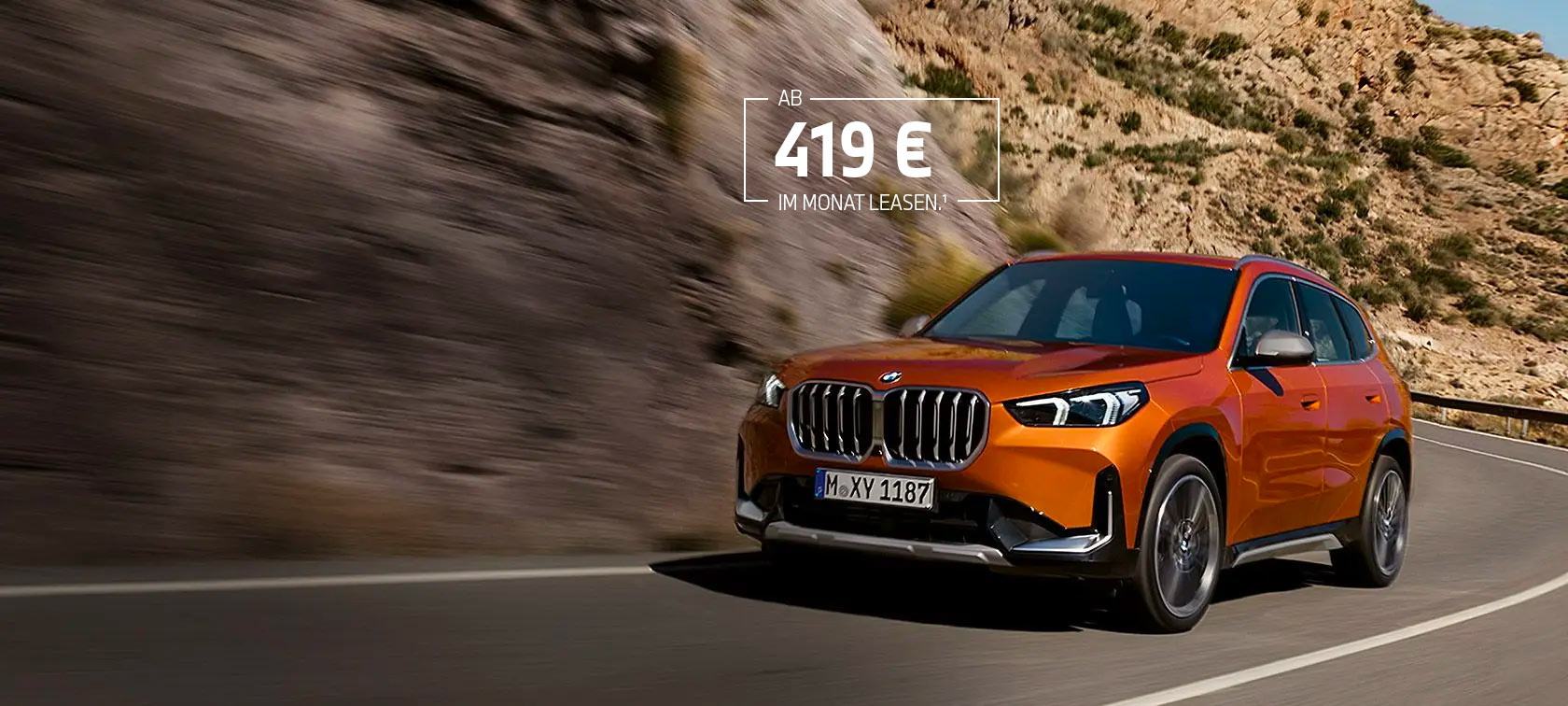 BMW X1 U11 xLine Utah orange metallic Dreiviertel-Frontansicht fahrend auf Landstraße