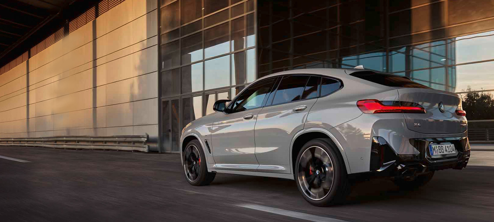 Fahrender grauer BMW X4 SUV G02 dreiviertel Heck-Ansicht.