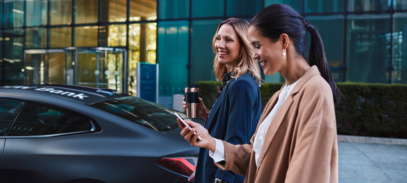 Zwei sich unterhaltende Frauen lachen gemeinsam vor BMW Zwei sich unterhaltende Frauen lachen gemeinsam vor BMW
