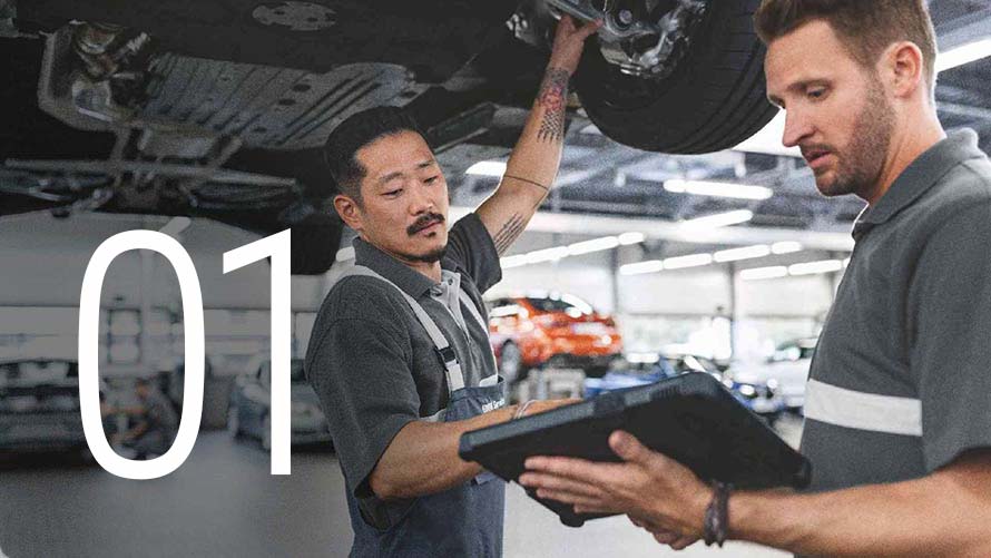 Zwei Männer begutachten in einer BMW Servicewerkstatt die Unterseite eines Fahrzeugs.