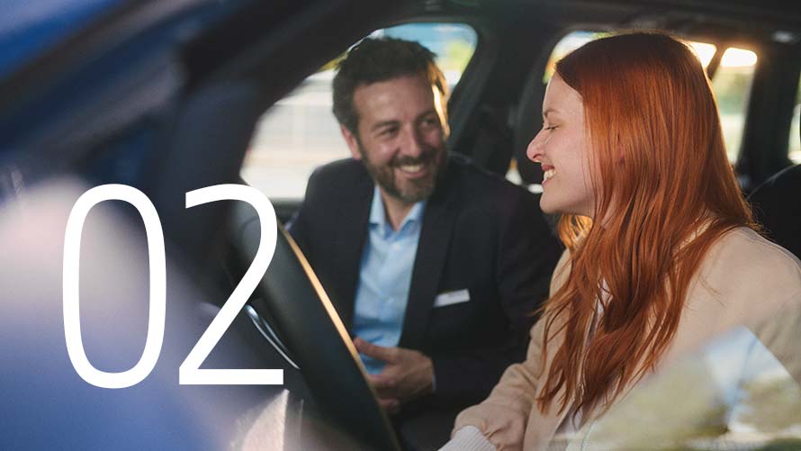 Ein Mann und eine Frau stehen auf dem Parkplatz eines BMW Service Partner und betrachten ein Tablet.